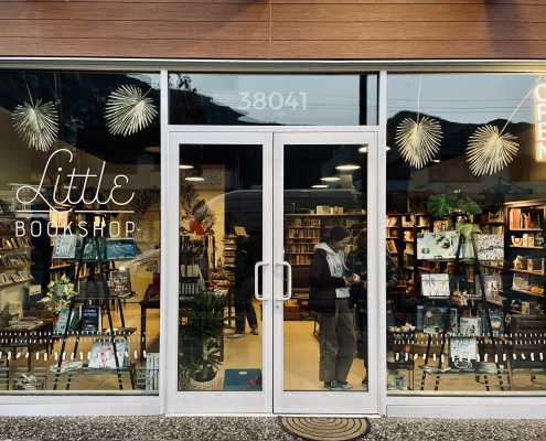 This is a photo of Little Bookshop's storefront in Squamish, B.C. There are shoppers inside talking to one another as they browse books.