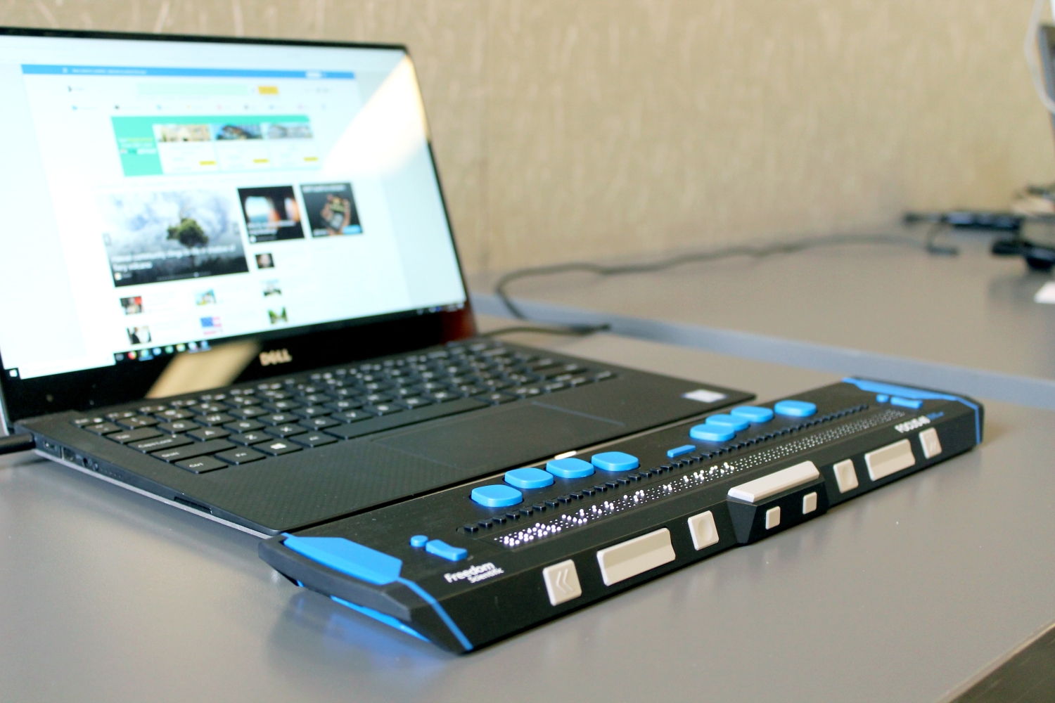 Image of a black laptop computer with a braille assistive technology devise in-use